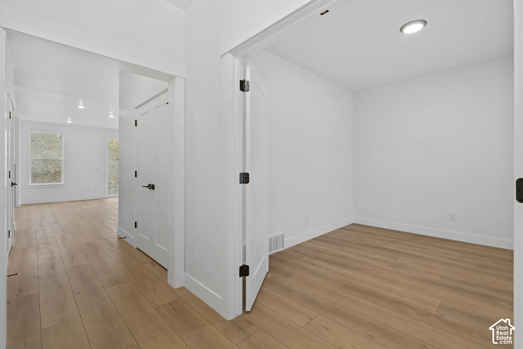 Neutral interior featuring wood-finish flooring, recessed lighting, and solid-core doors with matte black hardware