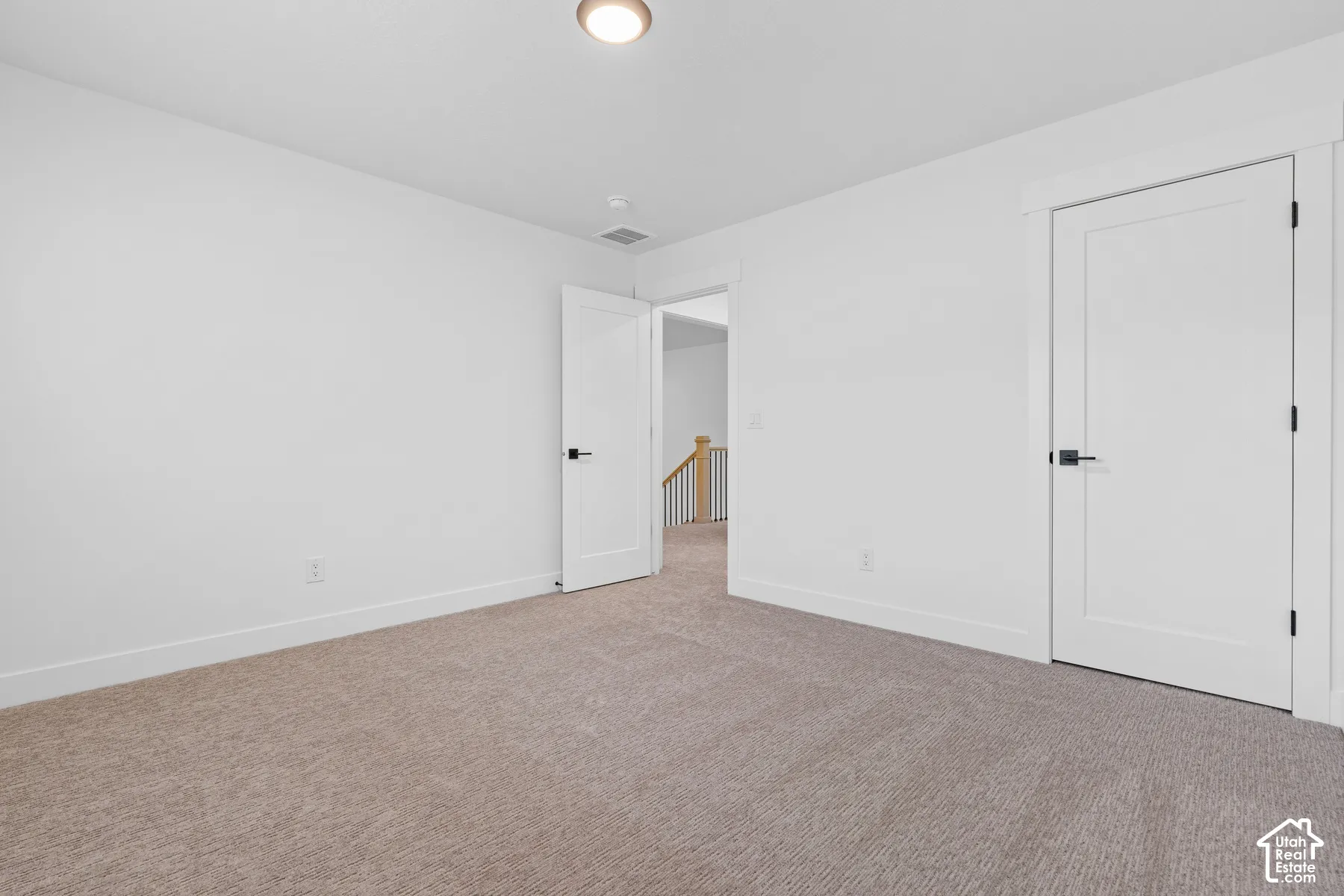 Neutral interior featuring carpeting, solid-core shaker-style doors, matte black hardware, and overhead flush-mount lighting