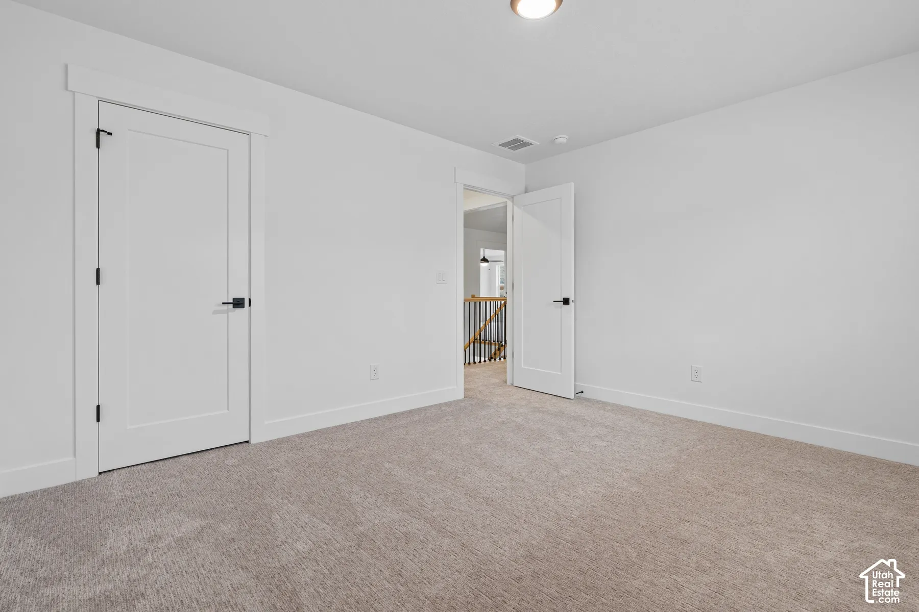 Neutral-toned carpet flooring, solid-core doors with matte black hardware, and thick-profile door casing