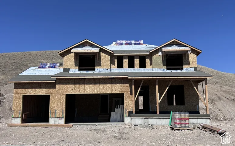 Two-story residential structure featuring wood-sheathed exterior walls, a covered front porch with timber bracing, and a multi-gabled roofline