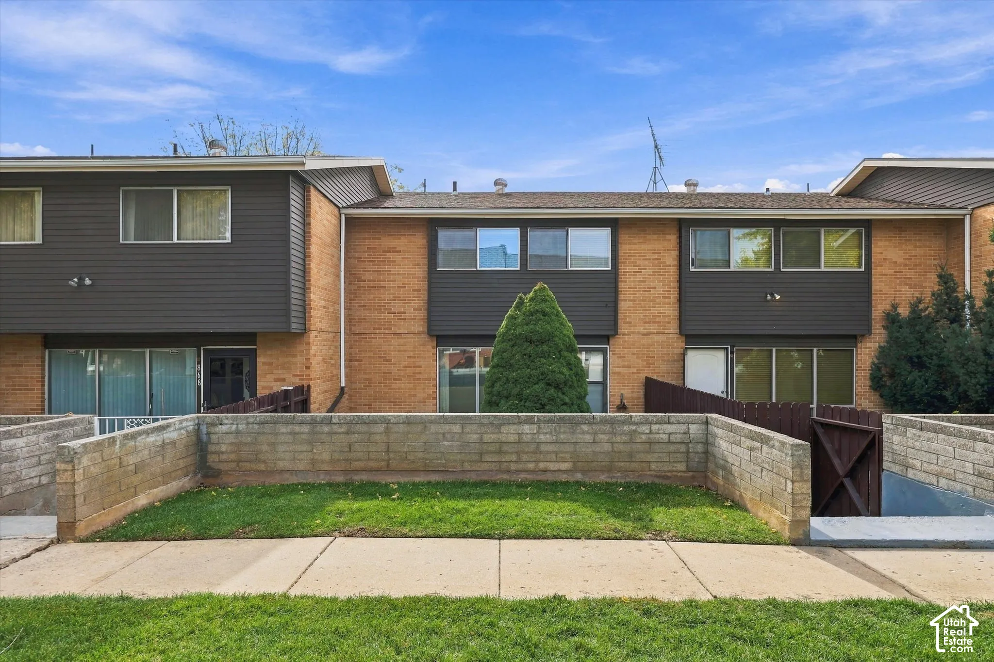Multi-level exterior featuring brick masonry and horizontal siding, private walled patio, and concrete hardscaping