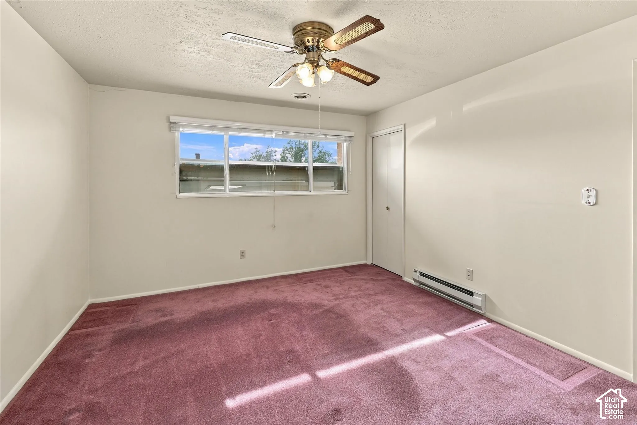 Interior room featuring wall-to-wall carpeting, a ceiling fan with integrated lighting, a sliding door closet, and a multi-pane horizontal window