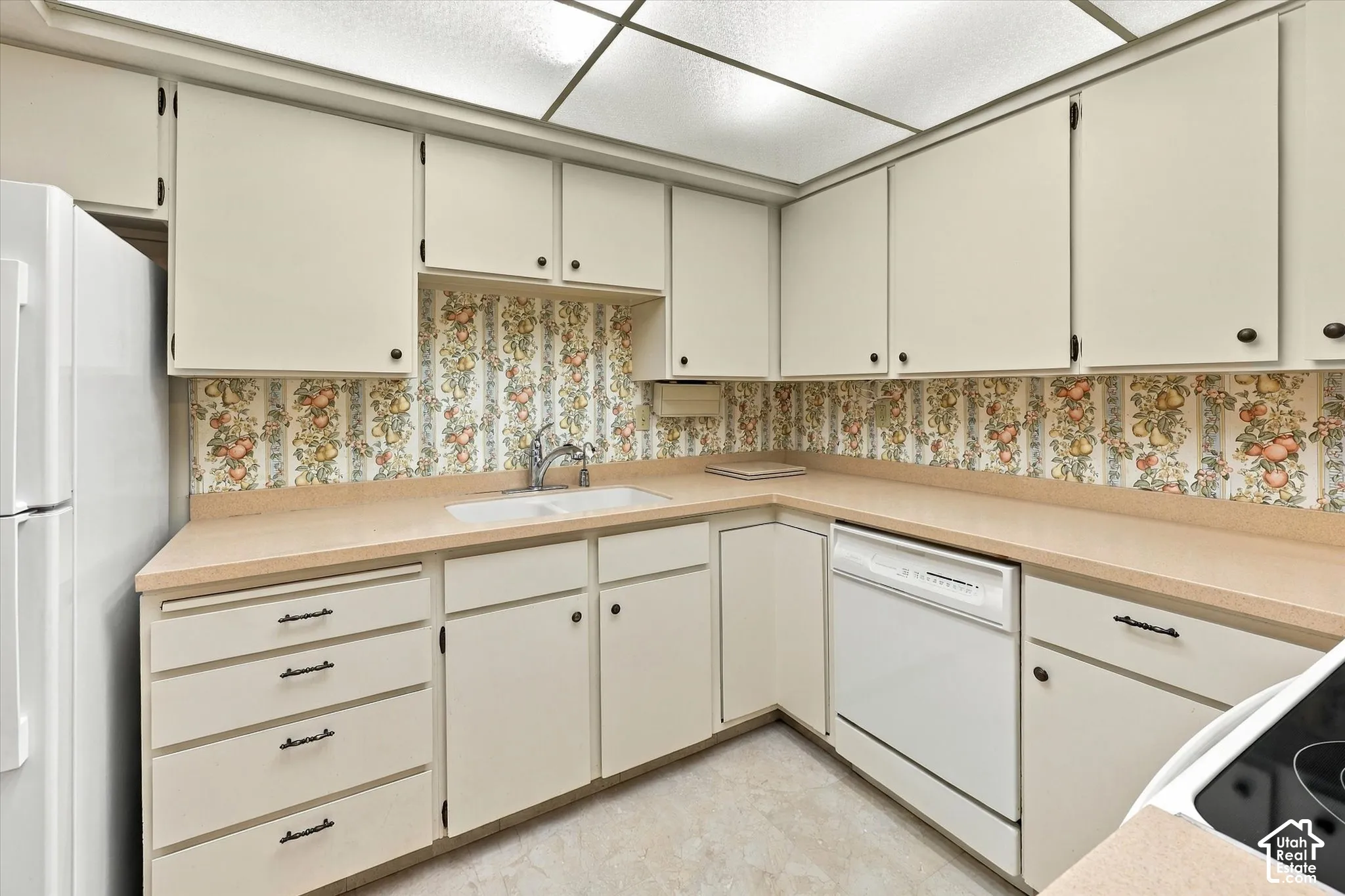 Kitchen featuring flat-panel cabinetry, solid surface countertops, dual-basin sink with pull-down faucet, and integrated dishwasher