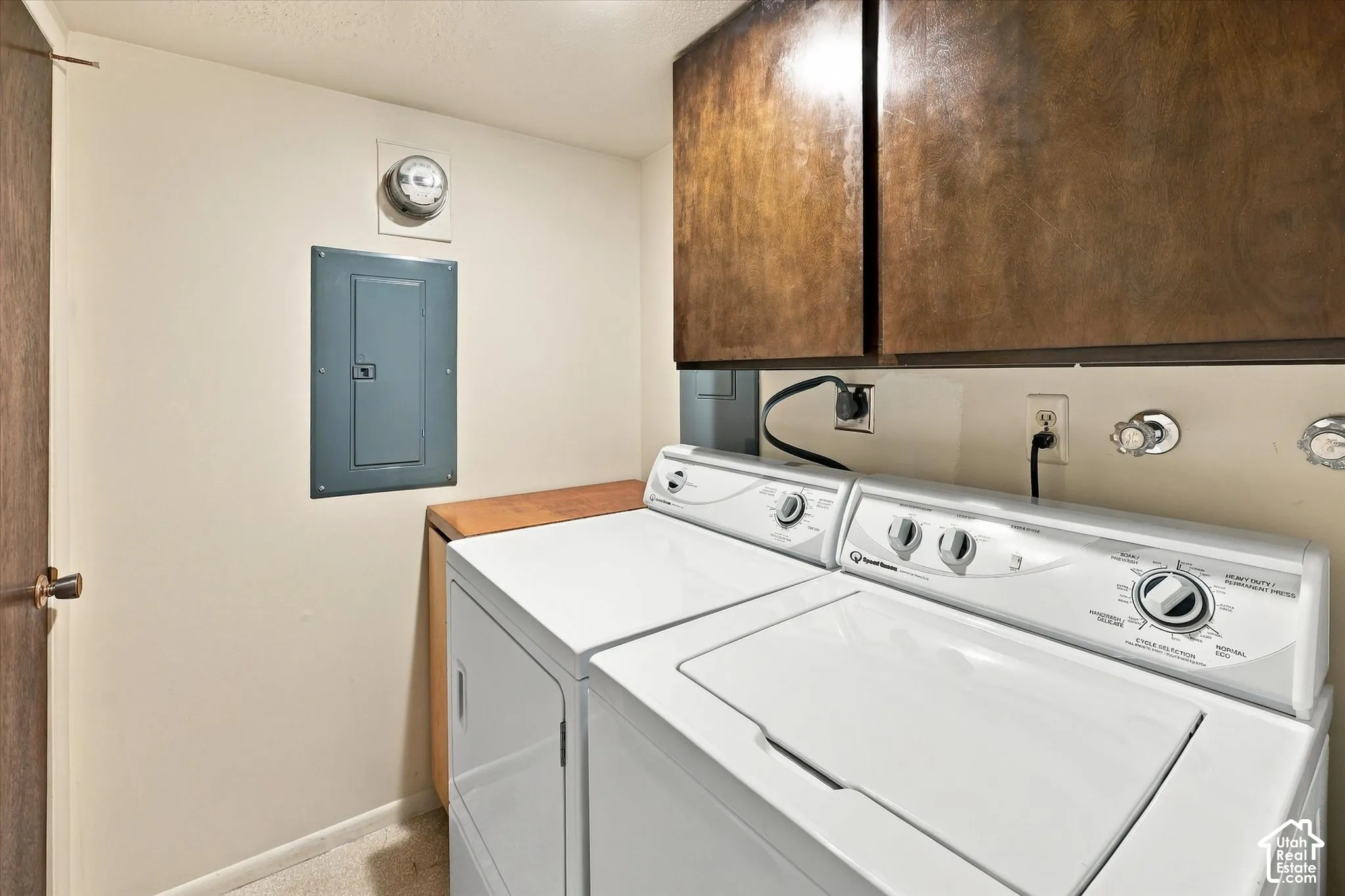 Dedicated laundry space featuring built-in wood-finish cabinetry, wall-mounted electrical panel, and dedicated washer and dryer hookups