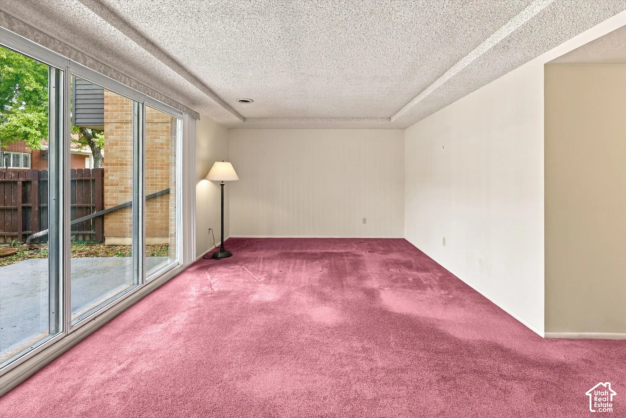 Large floor-to-ceiling windows with sliding glass doors, textured ceiling, and carpeting