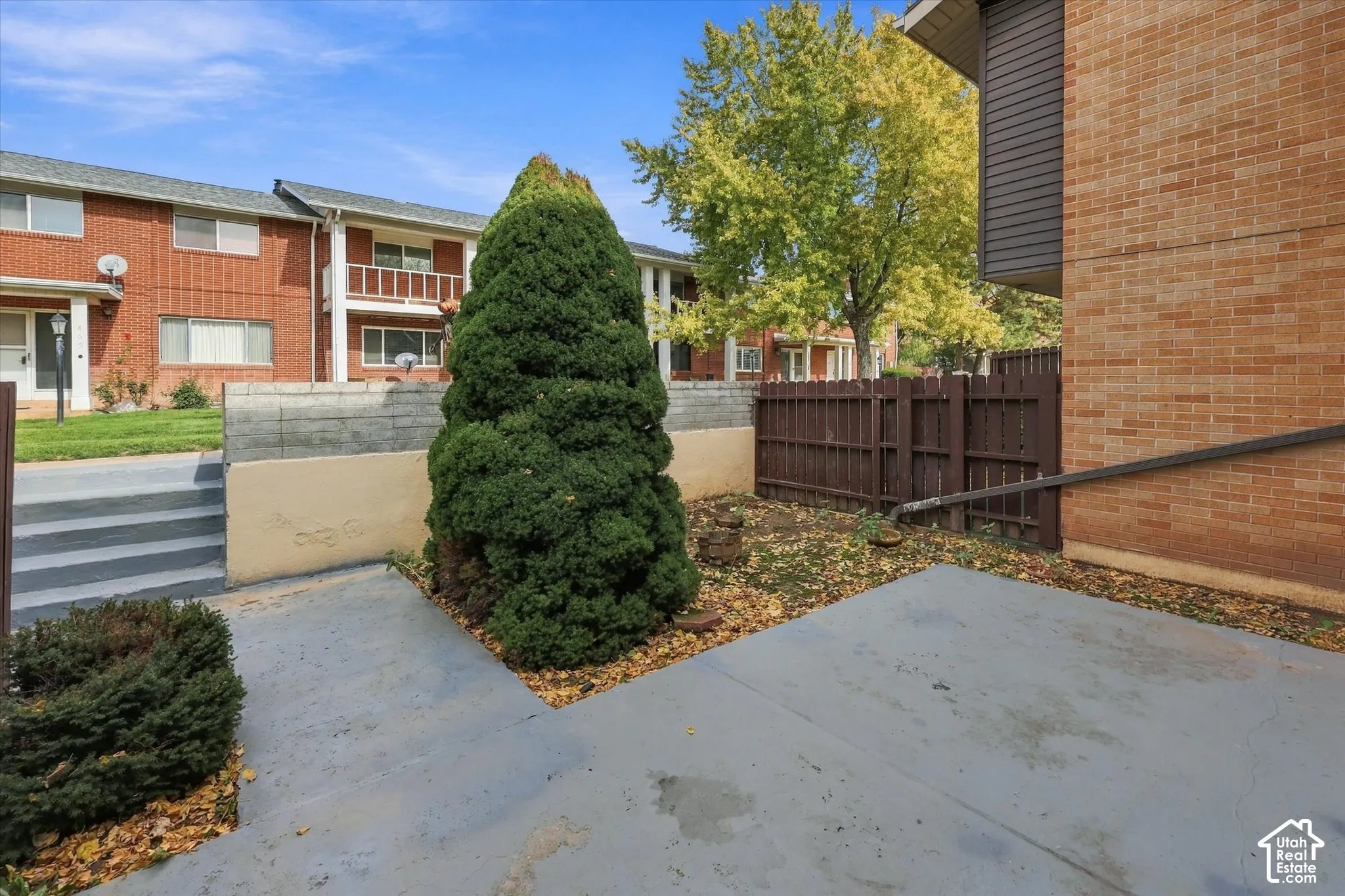 Private patio area featuring a concrete surface, enclosed by a wood privacy fence and a low concrete retaining wall