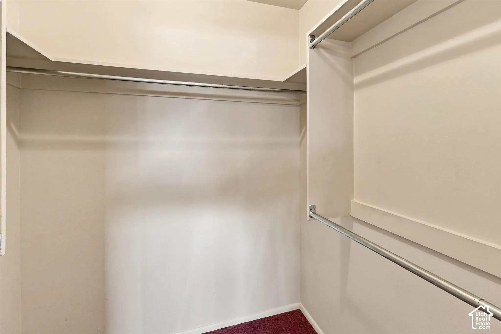 Walk-in closet featuring white wooden shelving and dual-tier metal hanging rods