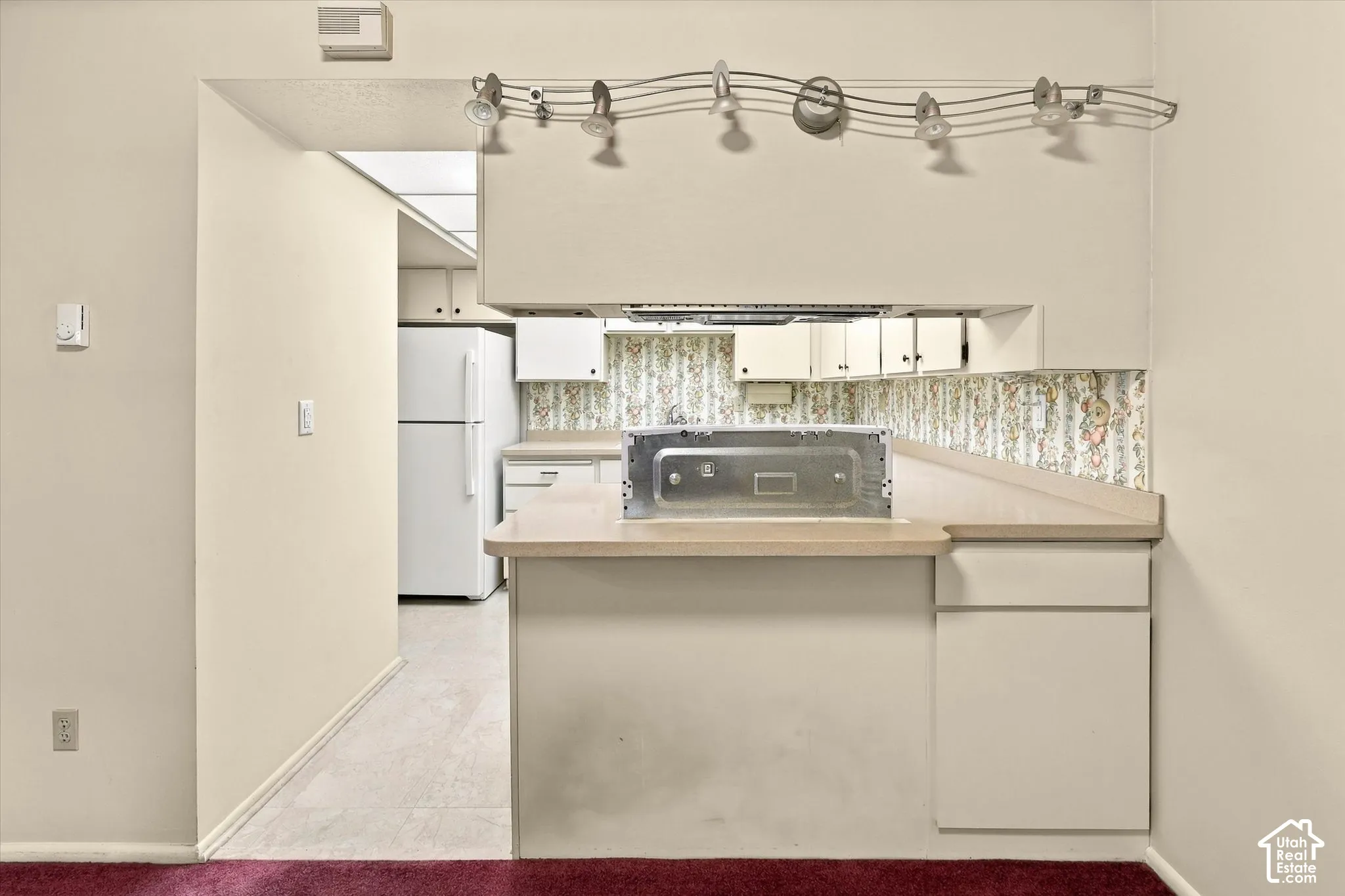 Kitchen featuring white cabinetry, laminate countertops, a track lighting fixture, and a built-in cooktop