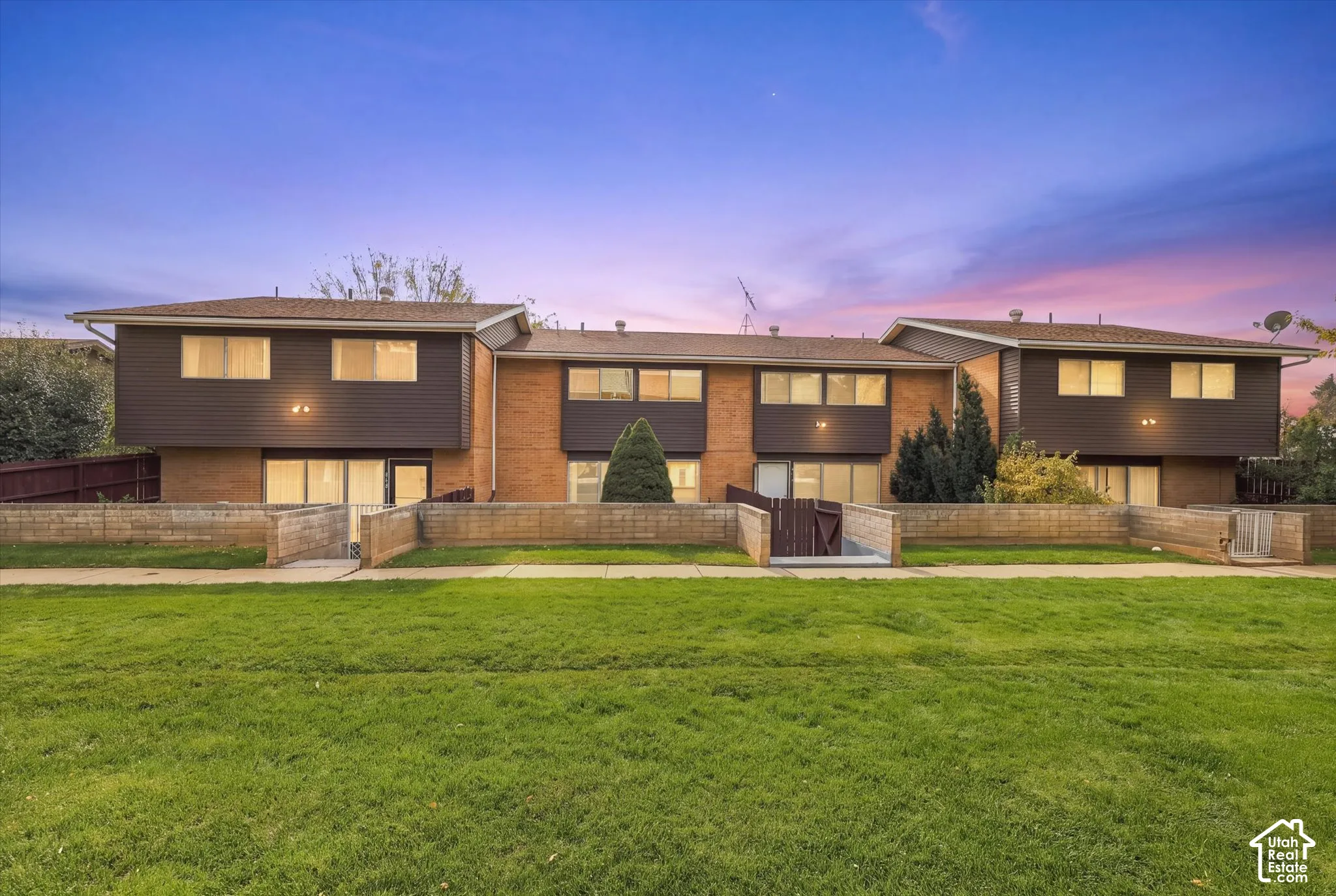 Multi-level exterior featuring brick and horizontal siding, low-profile rooflines, integrated masonry perimeter walls, and recessed entryways