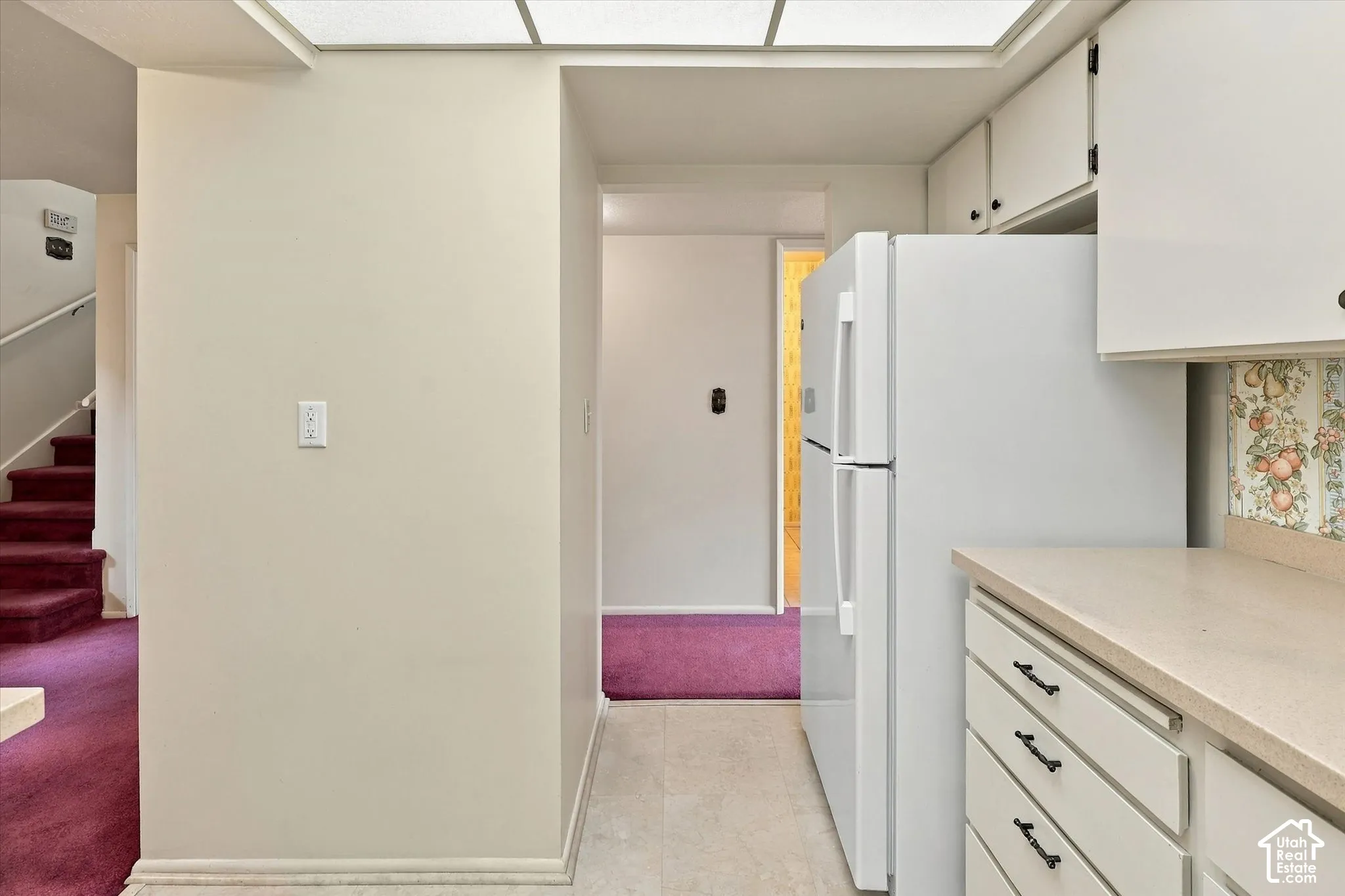 Kitchen featuring white cabinetry, solid-surface countertops, recessed ceiling lighting, and a top-mount refrigerator