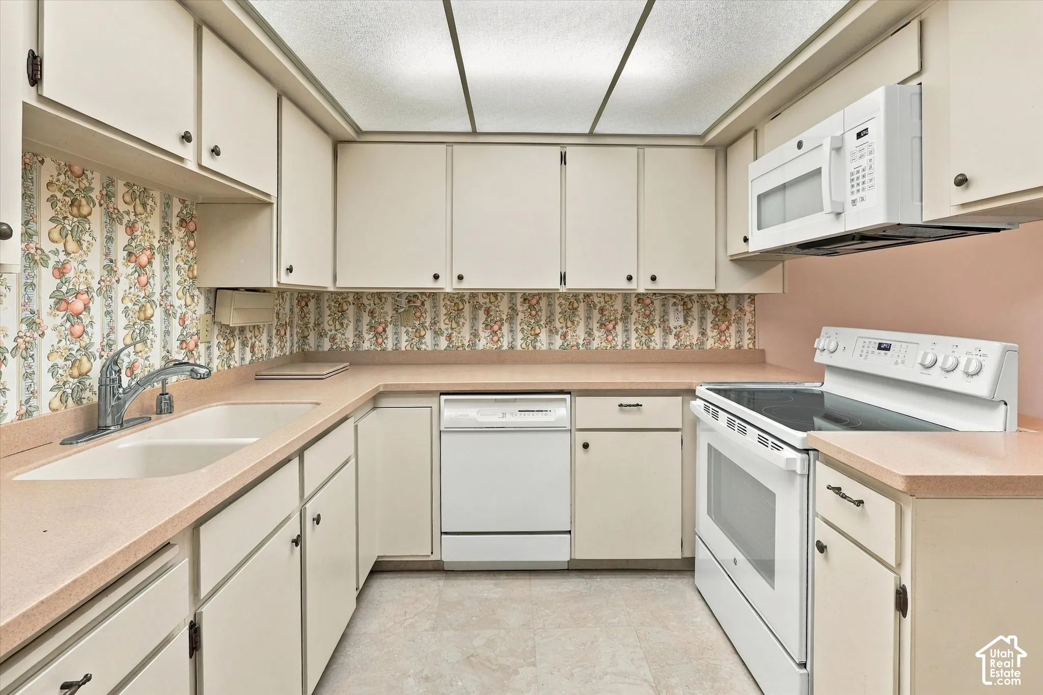 Kitchen featuring flat-panel cabinetry, solid-surface countertops, dual-basin sink with chrome faucet, integrated microwave, and built-in electric range
