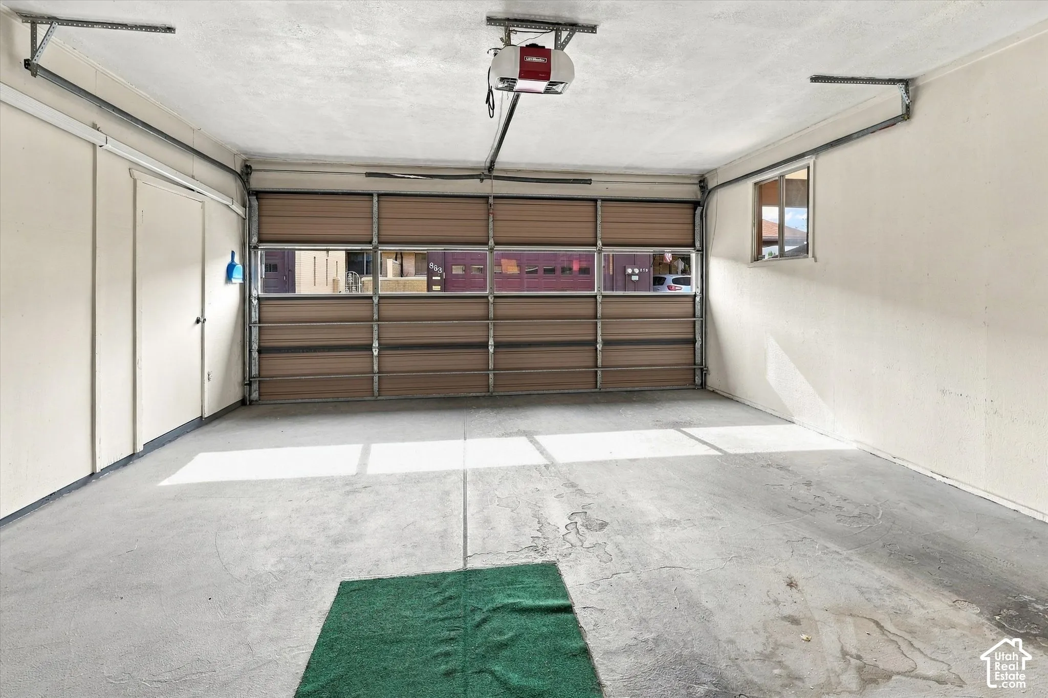 Enclosed two-car garage featuring a sectional door with windows, concrete flooring, automatic garage door opener, and a side-wall window