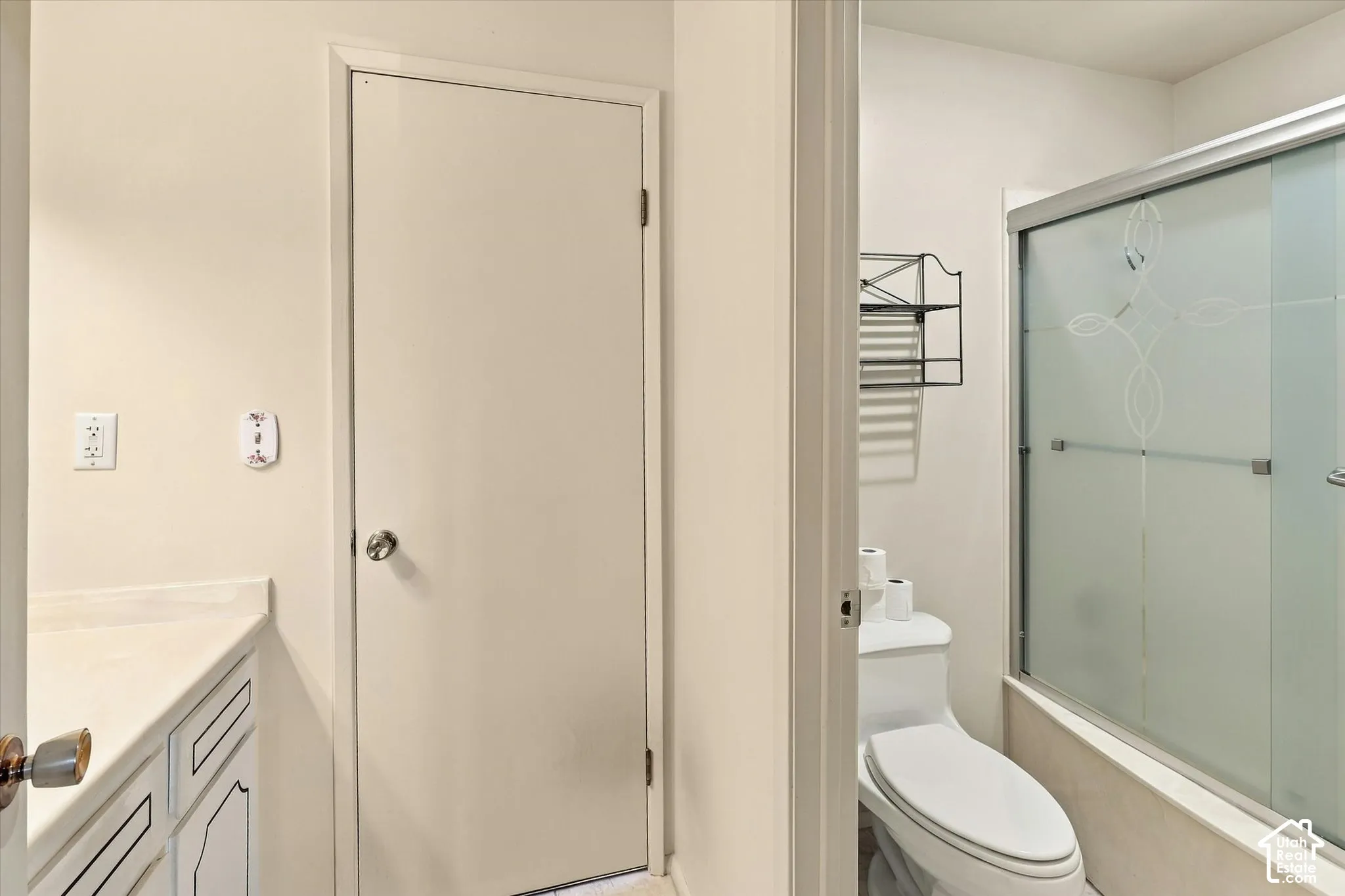 Bathroom featuring a vanity with integrated countertop, enclosed shower with sliding frosted glass doors, and a porcelain toilet