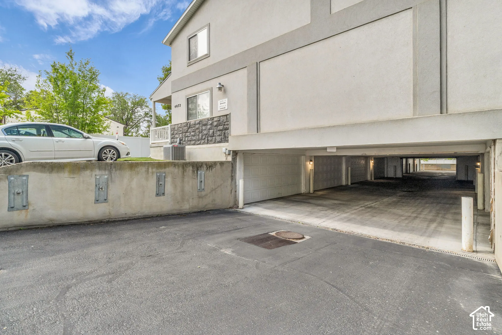 Multi-level exterior featuring stucco siding, stone veneer accents, and a covered parking area with multiple garage bays