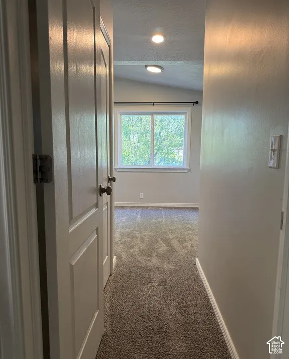 Neutral wall color, carpeted flooring, dual recessed lighting fixtures, and a large window with an integrated curtain rod