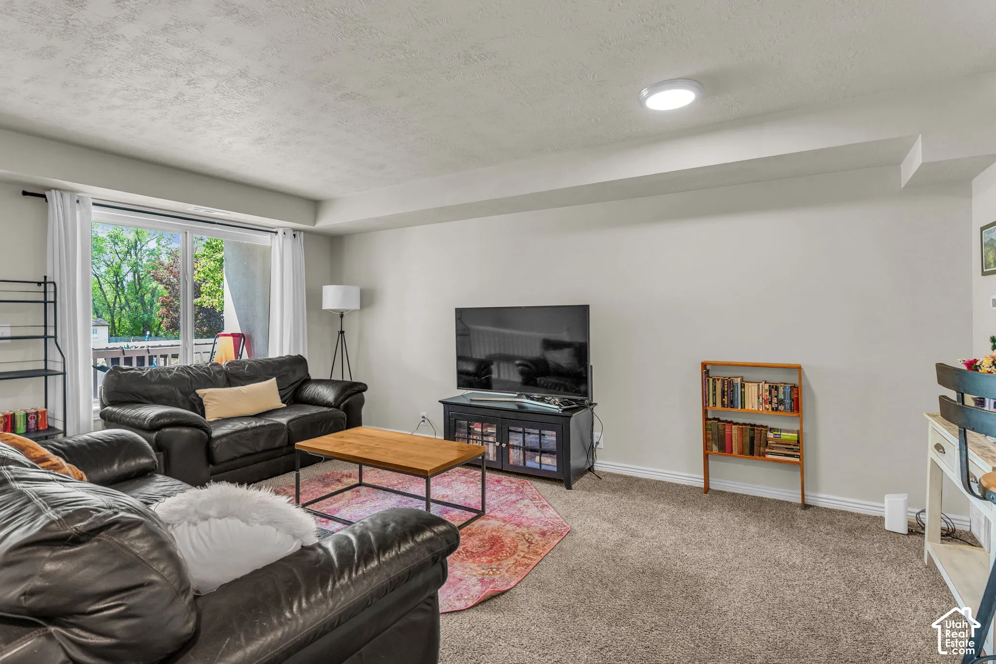 Neutral-toned interior space featuring neutral wall-to-wall carpeting, a large sliding glass door, and overhead lighting