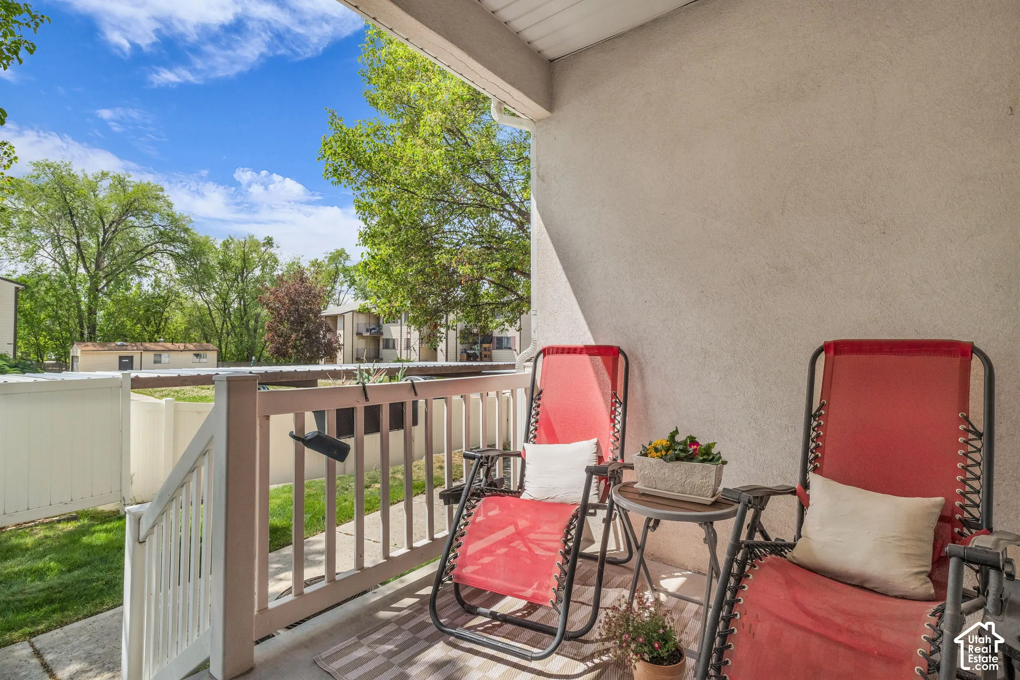 Covered patio featuring a concrete floor, white spindle railing, and a privacy fence