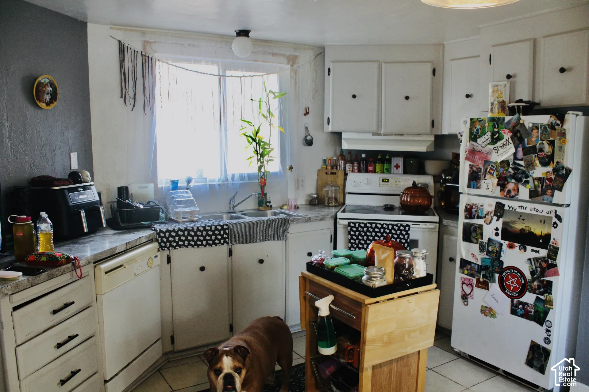 Kitchen featuring white cabinetry, stone-patterned countertops, a dual-basin sink, and tile flooring