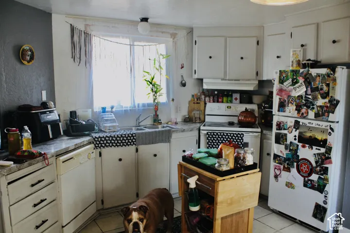 Kitchen featuring white cabinetry, stone-patterned countertops, a dual-basin sink, and tile flooring