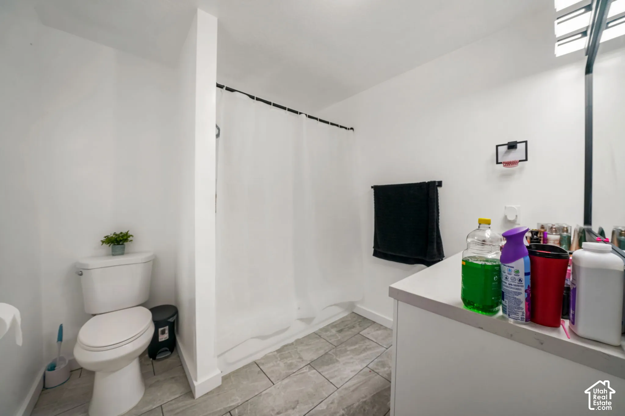 Bathroom featuring a tub-shower combination, grey tile flooring, a white vanity with a neutral countertop, and wall-mounted vanity lighting
