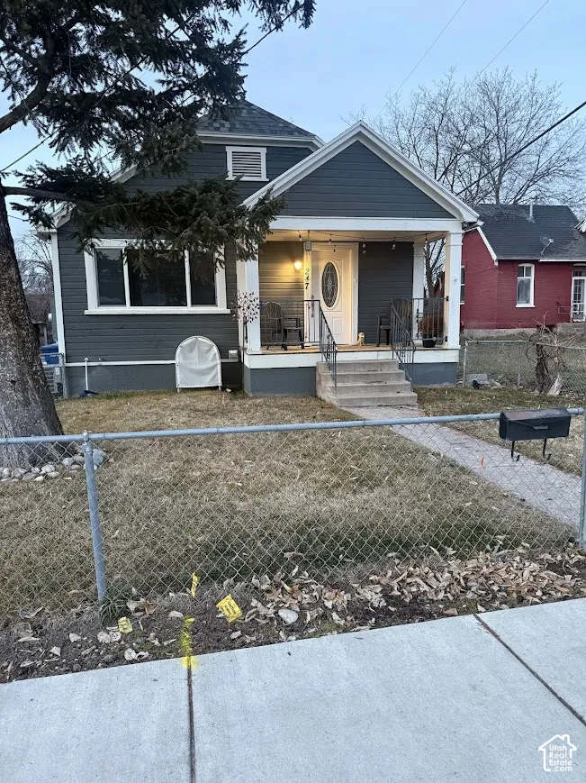 Single-story exterior featuring dark-toned horizontal siding, a covered front porch with gable roof detailing, and a concrete pathway