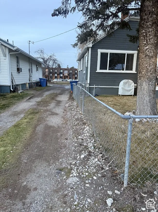 Gravel driveway bordering a fenced lawn with mature tree