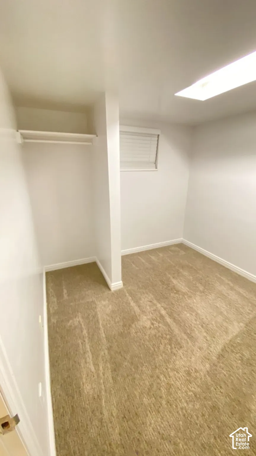 Neutral-toned wall-to-wall carpeting, recessed ceiling lighting, and a built-in closet with an integrated shelf
