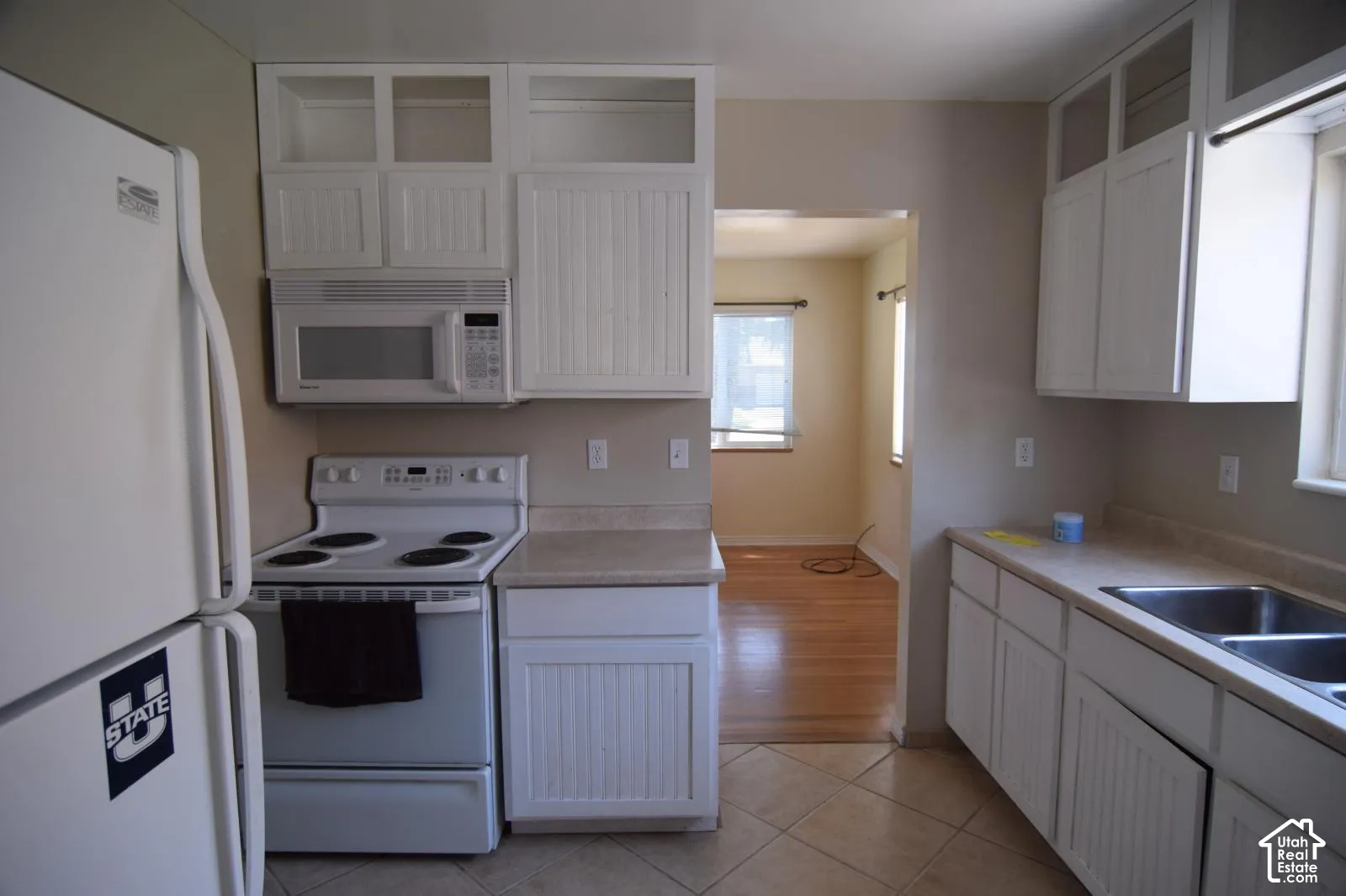 Kitchen featuring white cabinetry with beadboard detailing, solid-surface countertops, built-in microwave, electric range, and tile flooring
