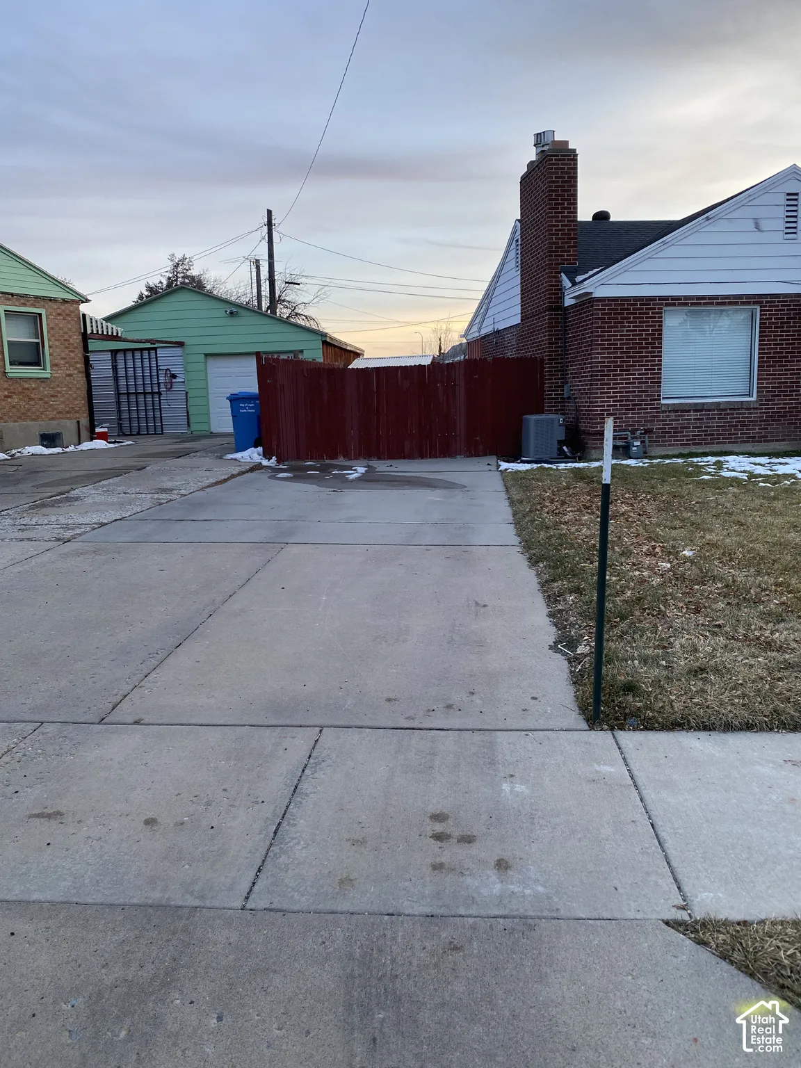 Exterior featuring brick masonry, a detached garage, a concrete driveway, and a red wood privacy fence
