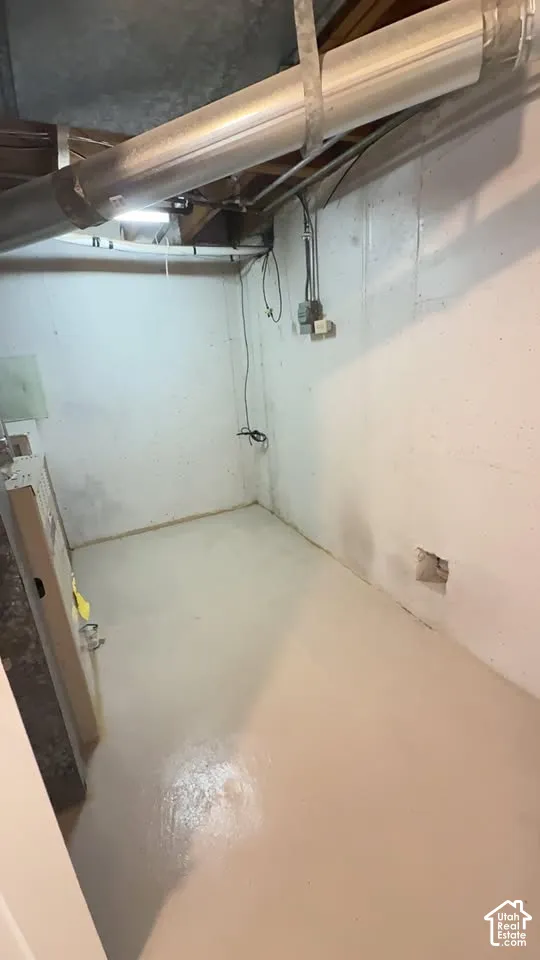 Unfinished space with painted concrete walls, concrete flooring, and exposed ceiling infrastructure