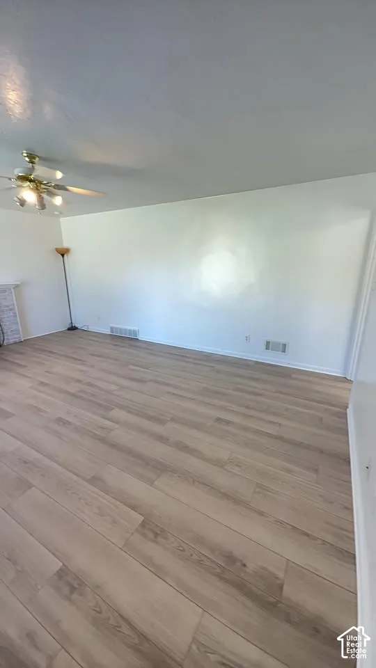Neutral-toned wood-finish flooring, white walls, and a ceiling-mounted light fixture with a fan