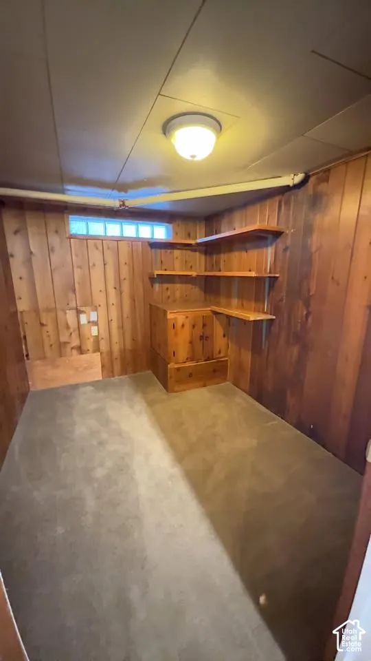Wood-paneled walls, built-in wooden cabinetry, multi-tiered corner shelving, flush-mount ceiling lighting, and a glass block window