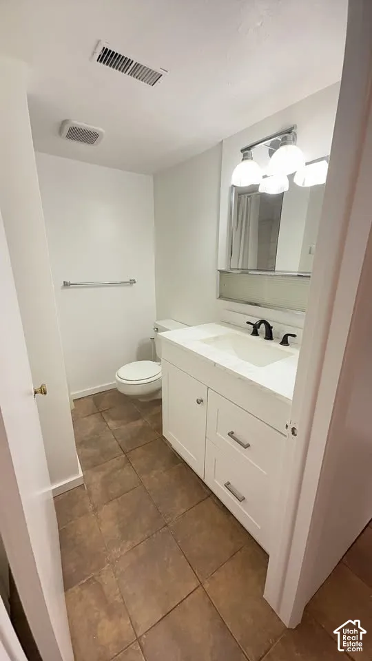 Bathroom vanity featuring a white cabinet, countertop with an integrated sink, three-light fixture, mirror, and tile flooring