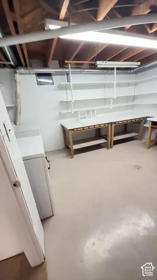 Utility room featuring painted concrete flooring, built-in wooden workbenches, and adjustable wall-mounted shelving