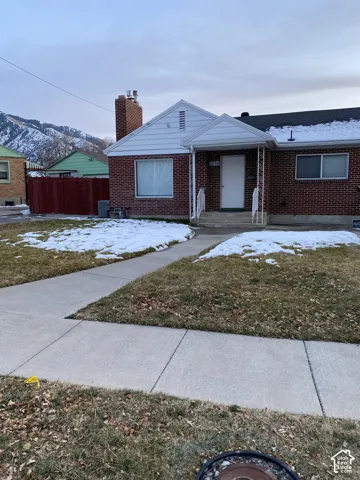 Brick exterior with a covered front porch, mountain backdrop, and concrete walkway