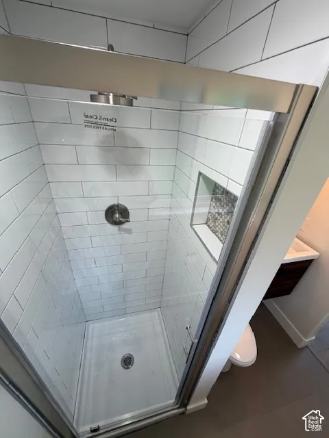 Shower enclosure featuring white subway tile, a metallic-finish shower head, a built-in tiled shower niche with decorative accent tile, and a sliding glass door