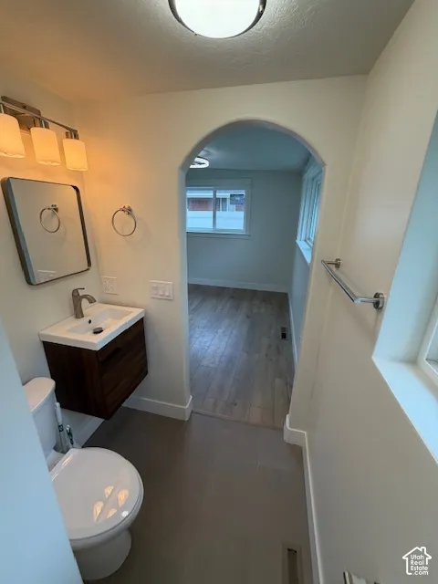Bathroom featuring a floating vanity with a vessel sink, chrome fixtures, arched doorway, and large-format tile flooring