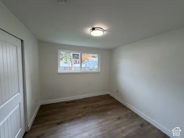 Room featuring wood-finish flooring, a flush-mount ceiling light fixture, a sliding-panel interior door, and a horizontal sliding window