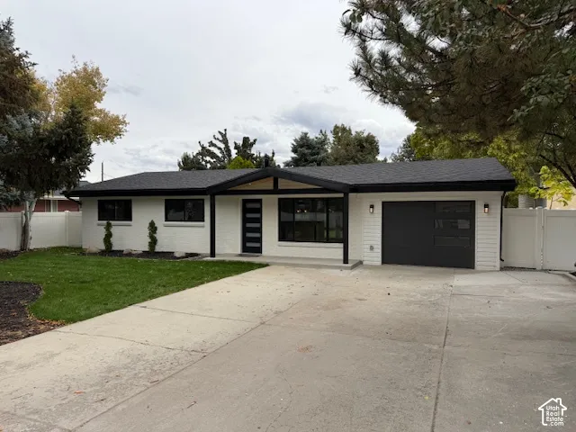 Single-story exterior featuring painted brick facade, gabled entryway, attached garage with horizontal window inserts, and concrete driveway