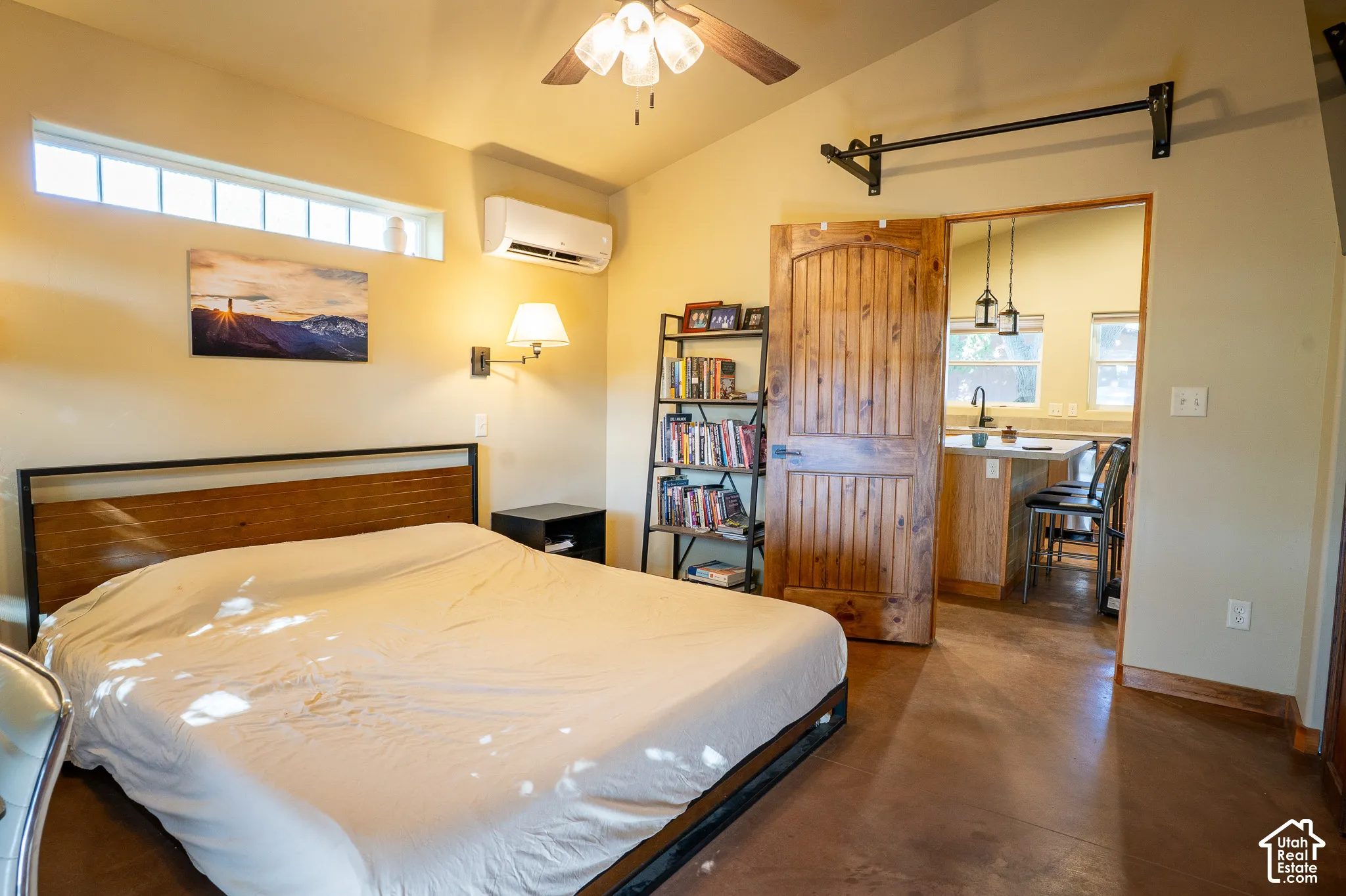 Vaulted ceilings with a ceiling fan, stained concrete flooring, clerestory windows, wall-mounted ductless heating and cooling unit, and a solid wood arched door