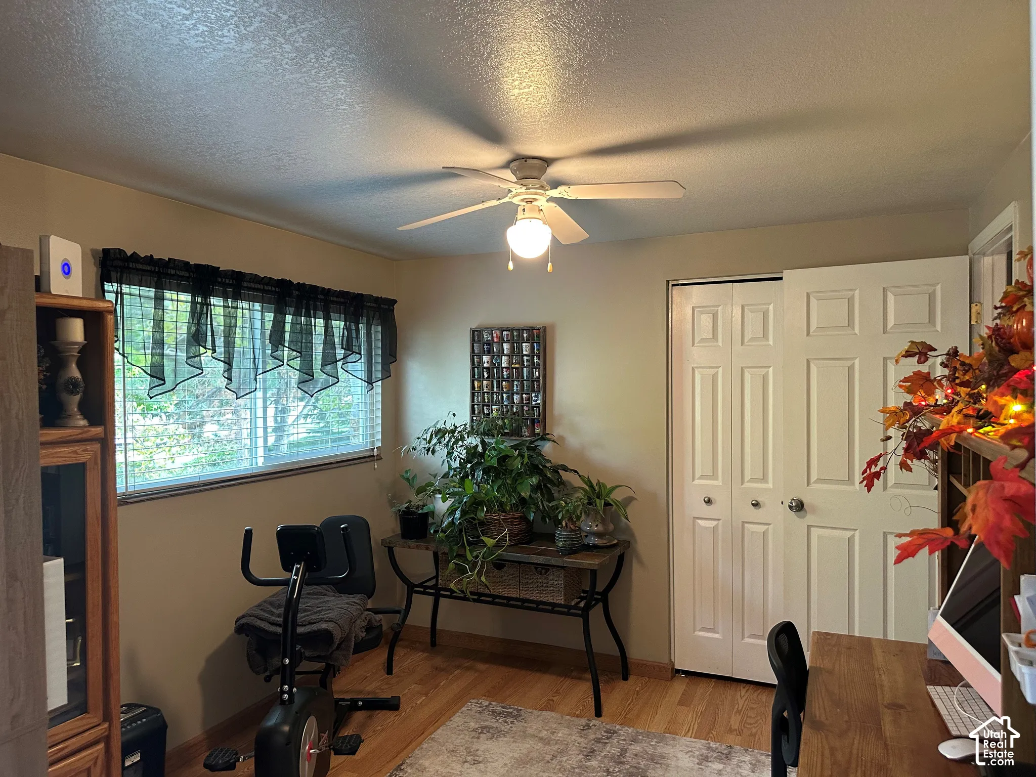 Neutral-toned walls, wood-finish flooring, white paneled closet doors, and a ceiling fan with integrated lighting