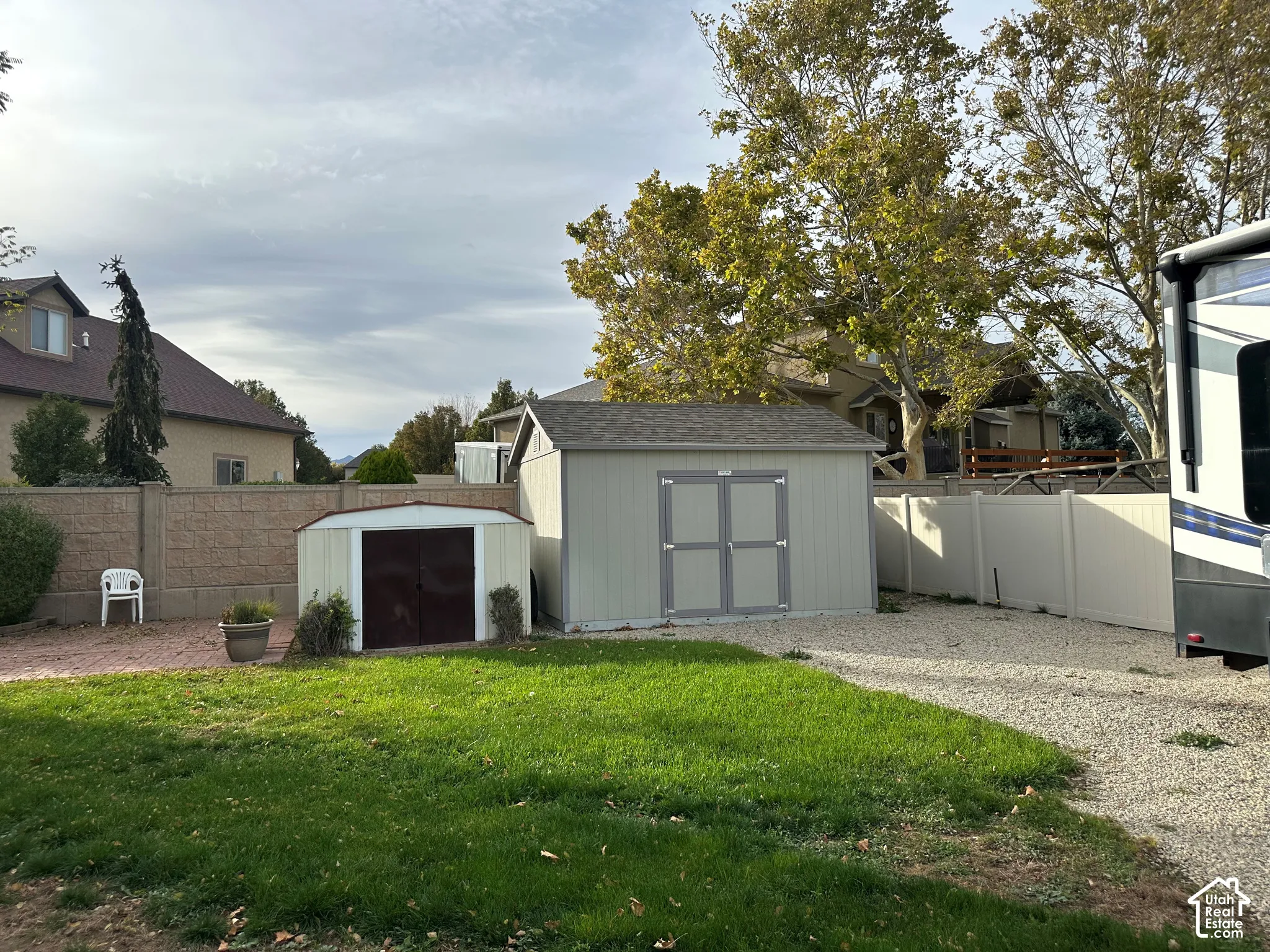 Backyard featuring a lawn, gravel surfacing, two storage sheds, and a perimeter fence