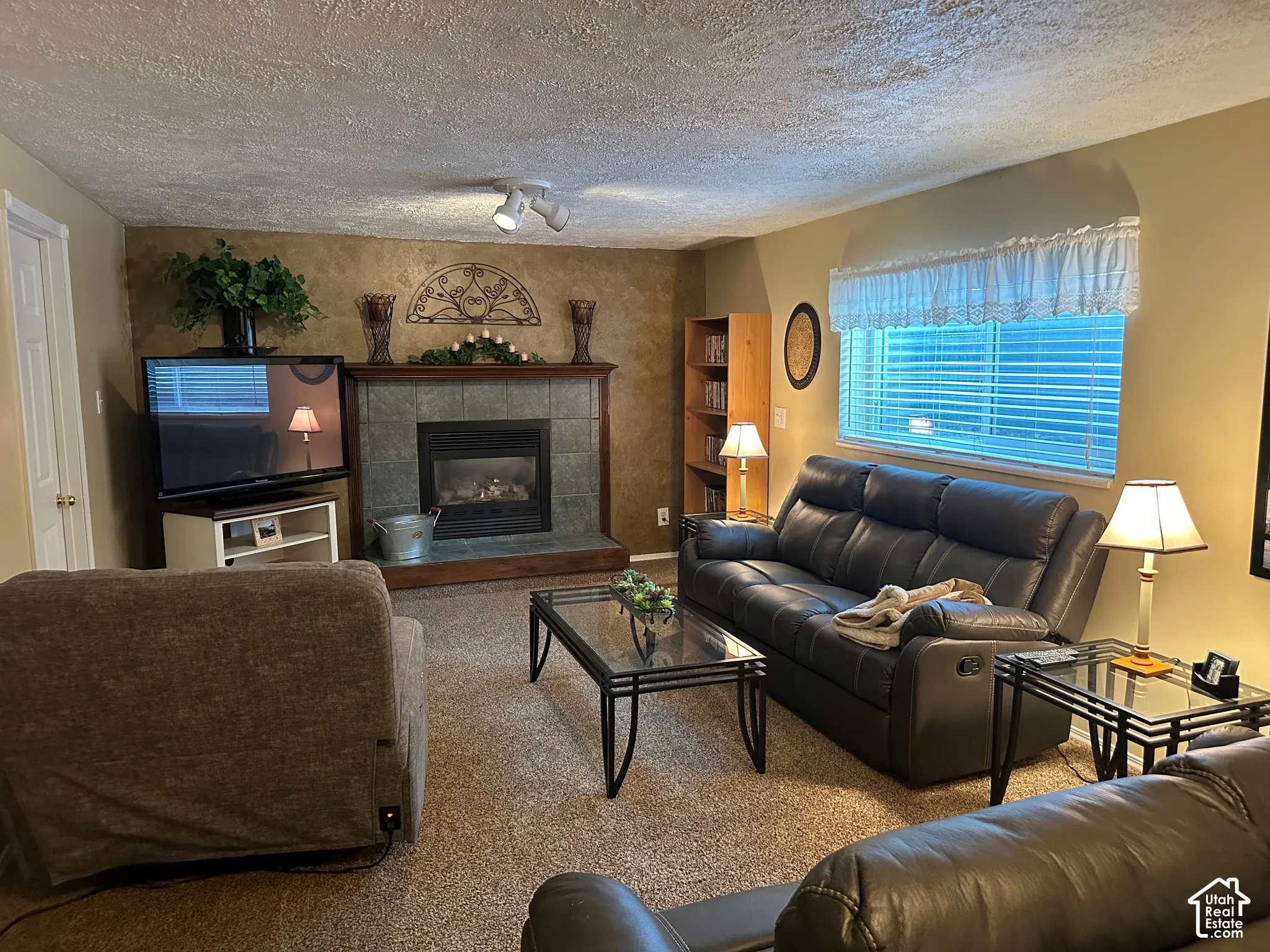 Fireplace with tile surround, wood-trim mantle, and integrated track lighting