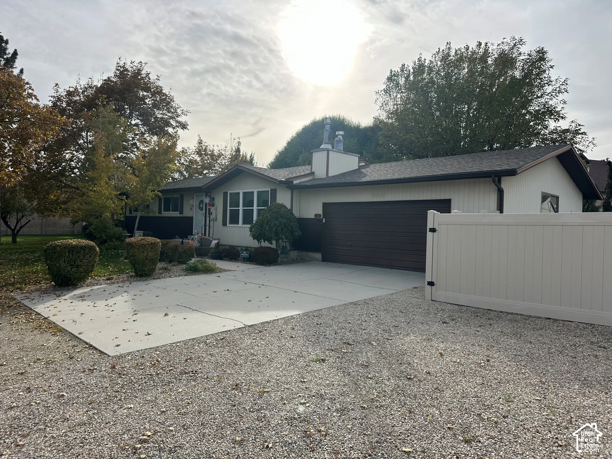 Ranch-style exterior featuring dual-tone siding, an attached two-car garage, a concrete driveway, and a white privacy fence