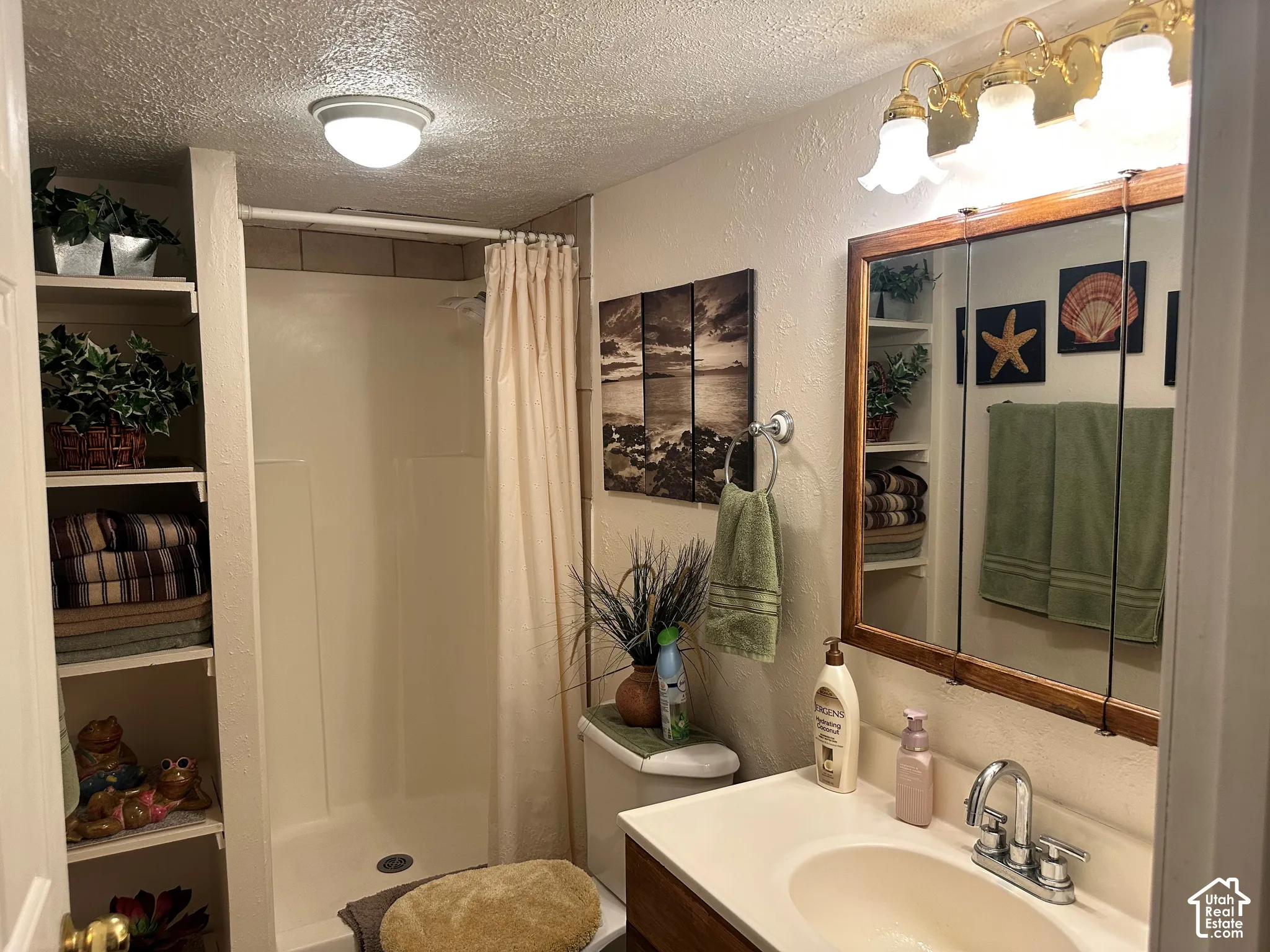 Bathroom featuring a built-in shelving unit, a shower stall with a surround, a wooden-frame medicine cabinet, and a vanity with a drop-in sink