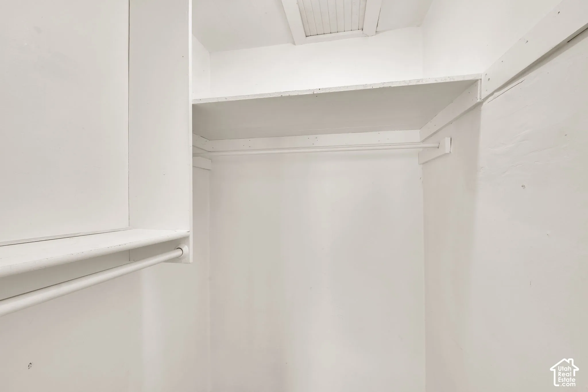 Storage area featuring dual-level shelving and integrated hanging rods