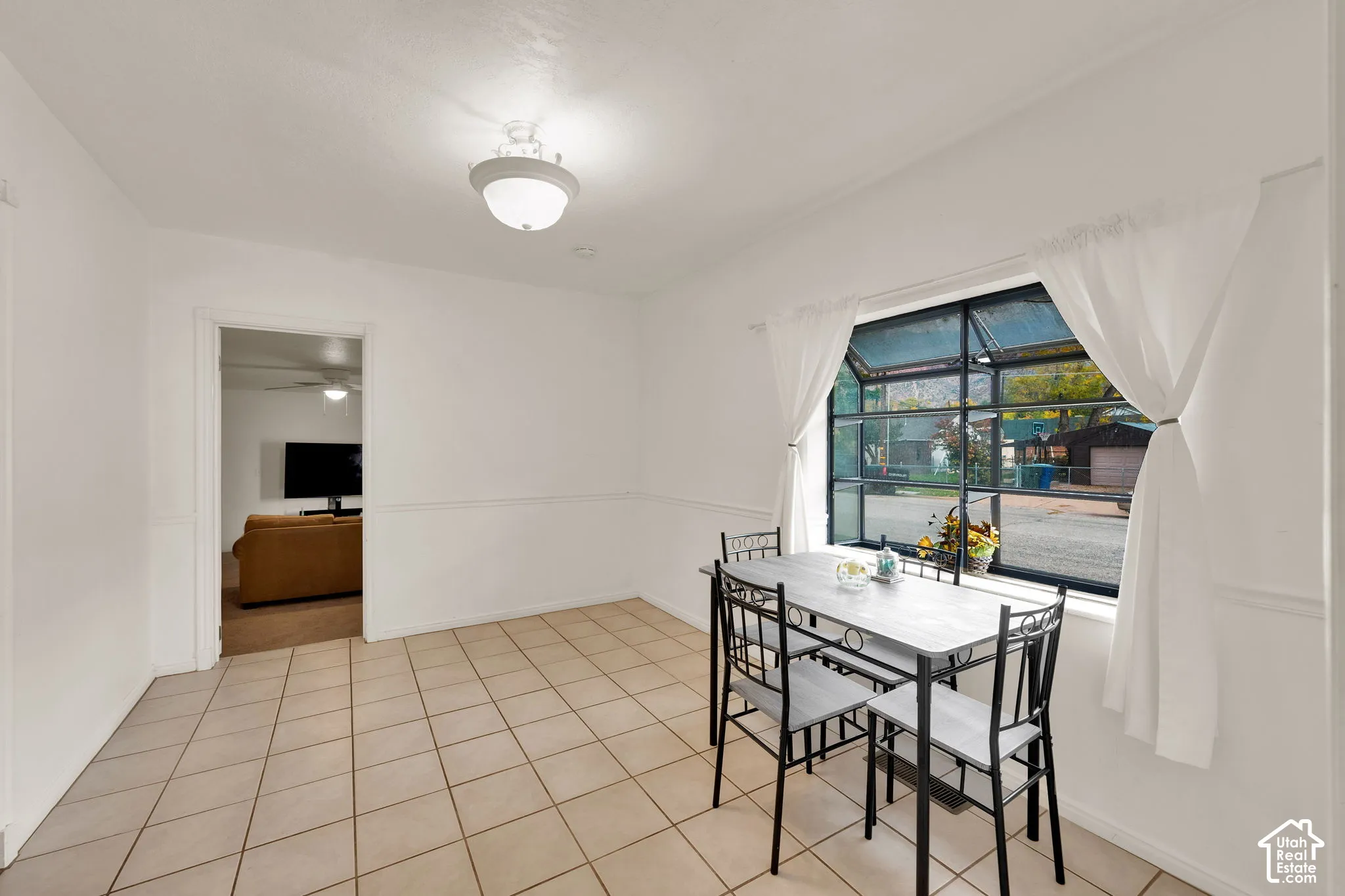 Neutral-toned tile flooring, chair rail molding, multi-pane window, and semi-flush mount ceiling lighting, used as dining room.