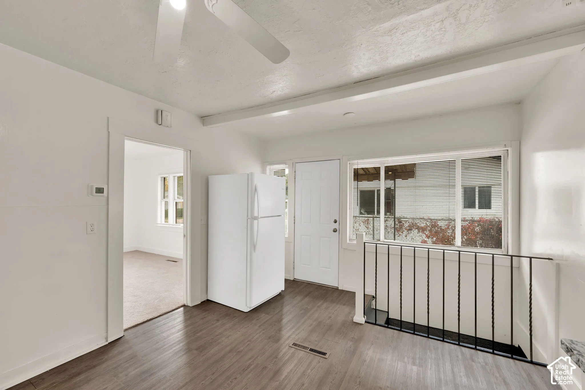 Wood-finish flooring, large picture window, metal stair railing, and ceiling-mounted fan