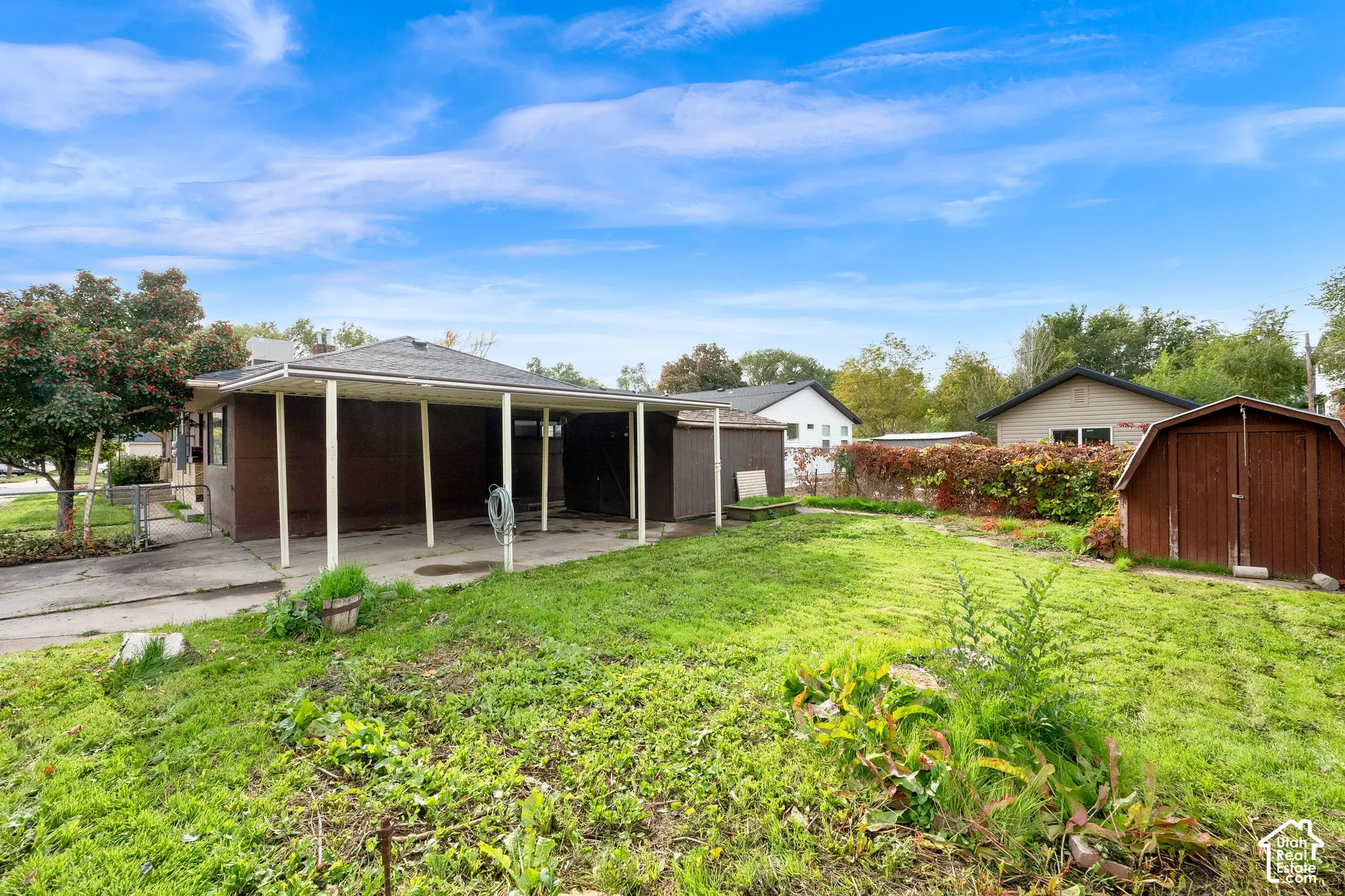 Exterior space featuring a covered carport, a detached storage shed, concrete surfacing, and fenced perimeter boundaries