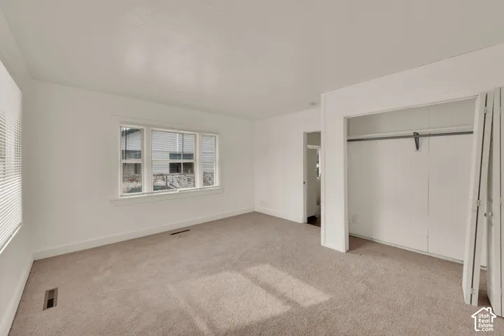 UNIT ON 15TH sTREE Neutral-toned carpeting, white walls, and a built-in closet featuring bi-fold doors and a metal clothing rod